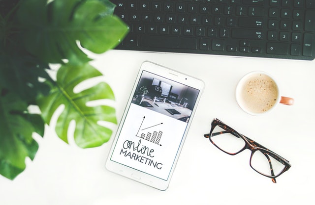 Handy mit "Online Marketing" auf dem Screen, Brille und Kaffee