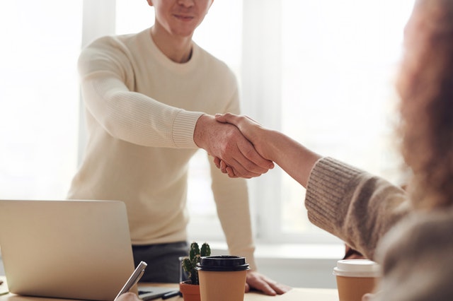 Zwei Menschen geben sich am Arbeitsplatz die Hand