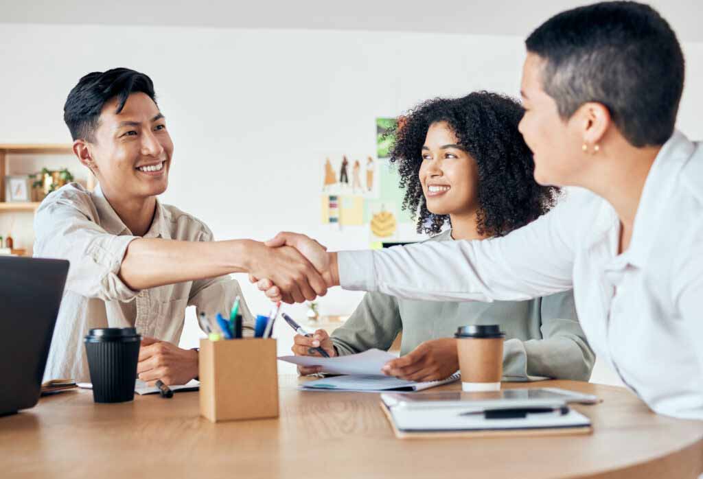 Teammeeting, zwei Mitarbeiter geben sich die Hand