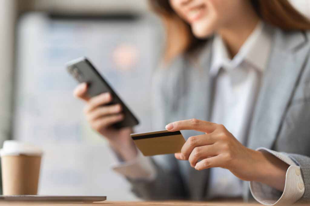 Frau am Handy mit Kreditkarte in der Hand